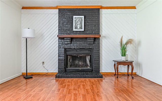 living room featuring wood-type flooring, a fireplace, and crown molding