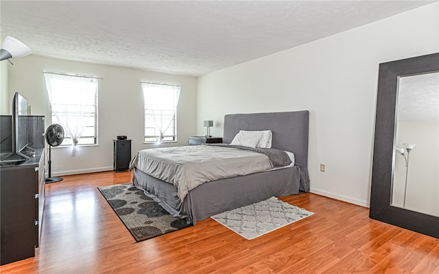 bedroom with light wood-type flooring and a textured ceiling