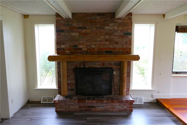 interior details with beam ceiling, hardwood / wood-style floors, a textured ceiling, and a fireplace