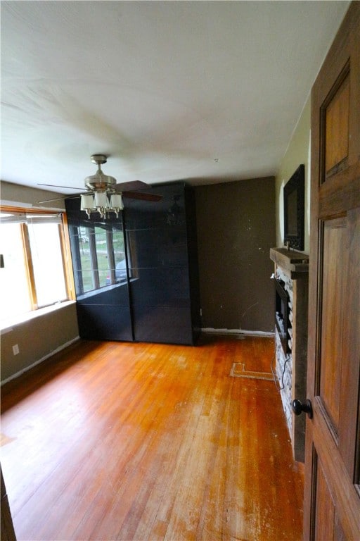 unfurnished living room with ceiling fan, a fireplace, and hardwood / wood-style floors