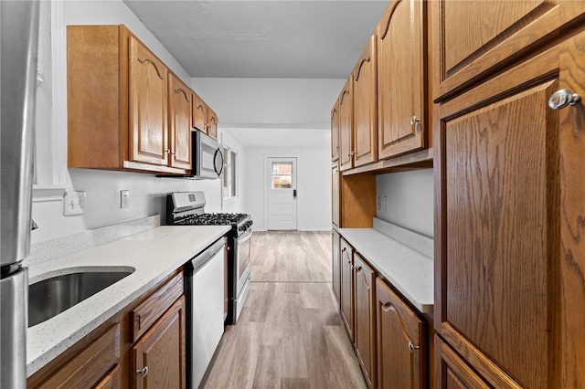 kitchen with light stone counters, light hardwood / wood-style floors, and appliances with stainless steel finishes