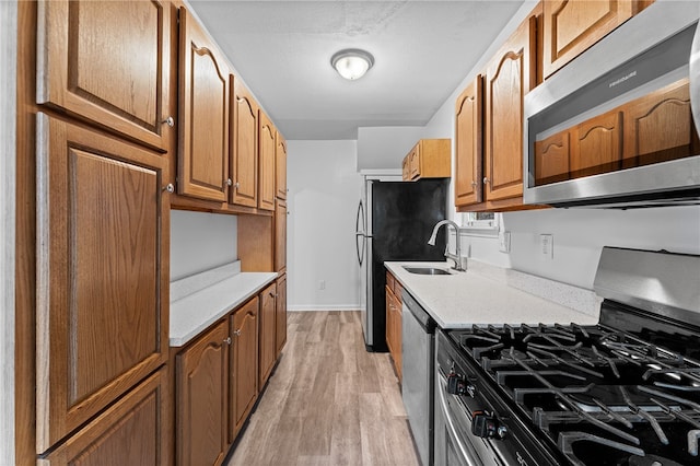 kitchen with sink, appliances with stainless steel finishes, and light hardwood / wood-style floors