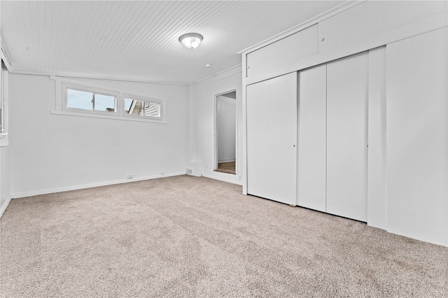 unfurnished bedroom featuring light carpet, lofted ceiling, and a closet