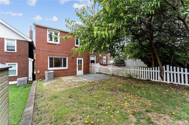 rear view of house with a patio, cooling unit, and a yard