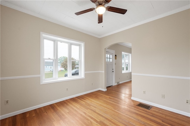 spare room featuring light wood-type flooring, a healthy amount of sunlight, crown molding, and ceiling fan