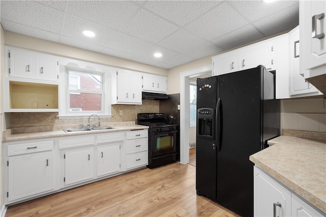 kitchen with black appliances, light hardwood / wood-style floors, sink, and white cabinets