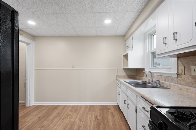 kitchen featuring light wood-type flooring, a paneled ceiling, sink, and white cabinetry