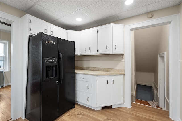 kitchen with light hardwood / wood-style floors, black refrigerator with ice dispenser, and white cabinetry