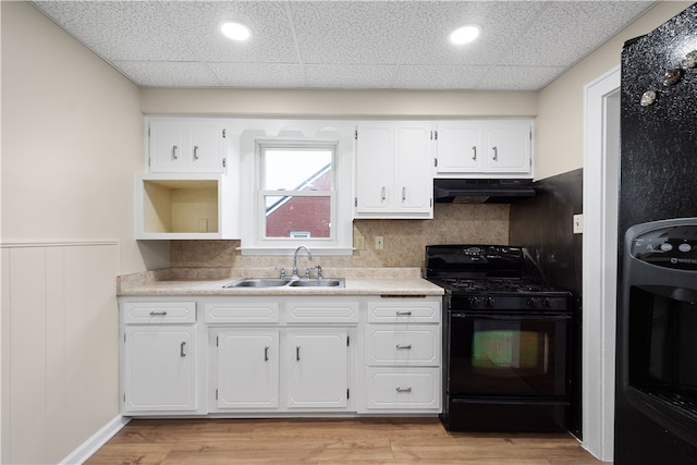 kitchen featuring black gas stove, sink, white cabinetry, light hardwood / wood-style flooring, and backsplash