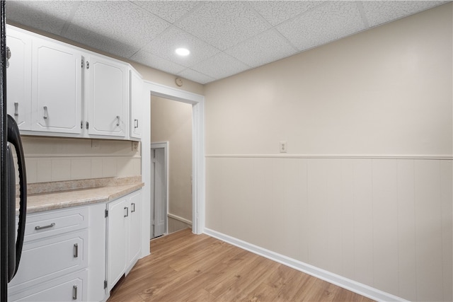 kitchen with white cabinetry, light hardwood / wood-style floors, and a paneled ceiling