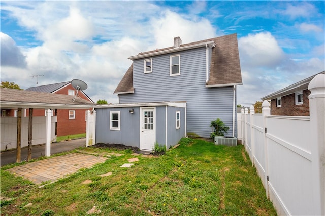 rear view of property with a lawn, central air condition unit, and a patio area