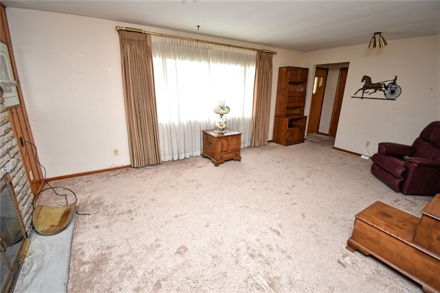 carpeted living room with a stone fireplace