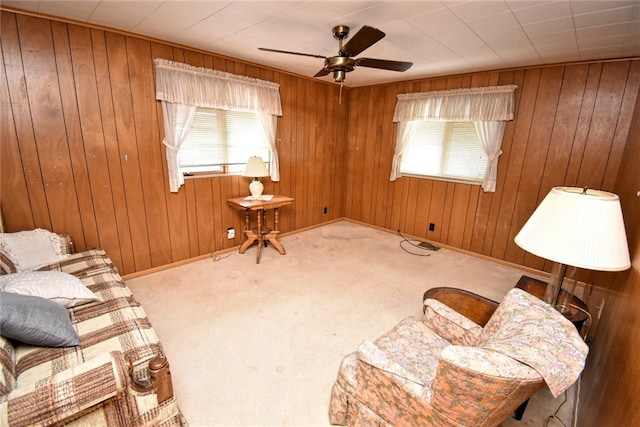 sitting room featuring carpet, wood walls, and ceiling fan