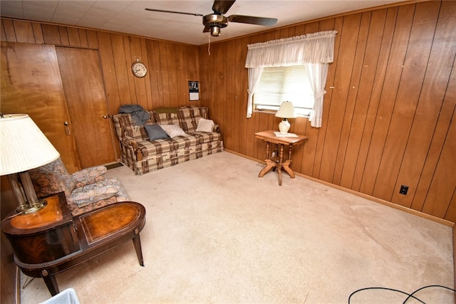 living area with carpet floors, wooden walls, and ceiling fan