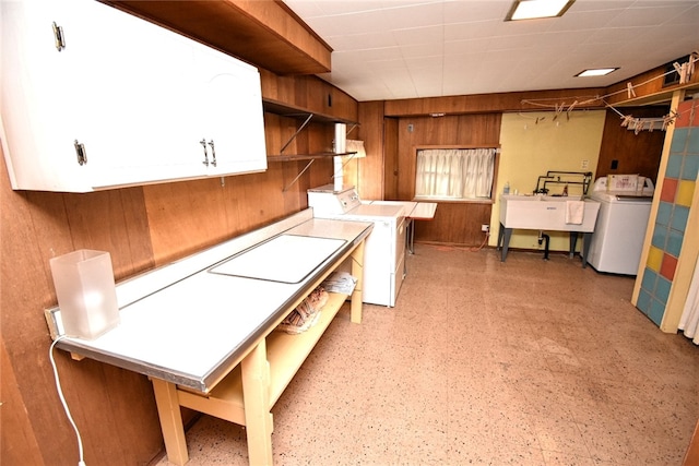 kitchen with wooden walls, sink, and washing machine and clothes dryer