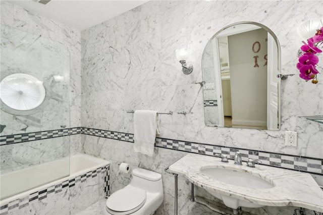 full bathroom with sink, tile walls, toilet, and tiled shower / bath