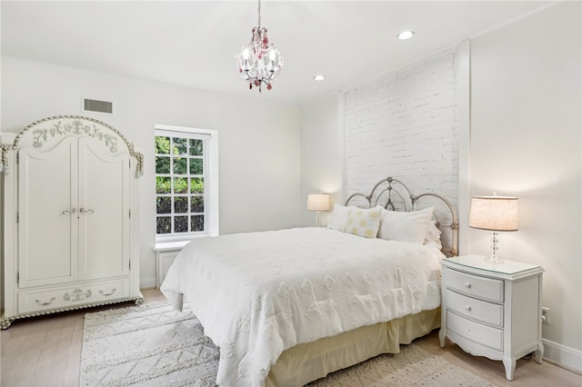 bedroom with a notable chandelier, light wood-type flooring, and crown molding