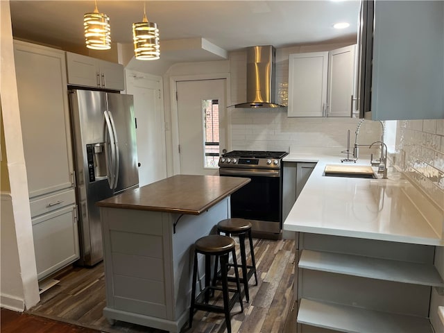 kitchen with dark hardwood / wood-style floors, sink, a kitchen island, wall chimney exhaust hood, and stainless steel appliances