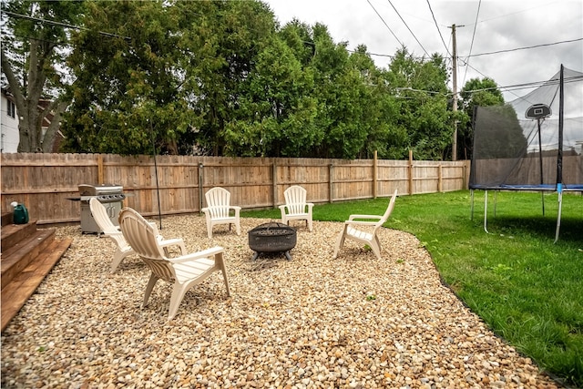 view of yard with a trampoline and an outdoor fire pit