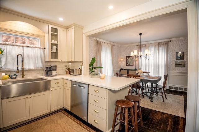 kitchen with dark wood-type flooring, sink, a notable chandelier, kitchen peninsula, and stainless steel dishwasher