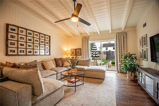 living room with wood-type flooring, beam ceiling, ceiling fan, and wooden walls