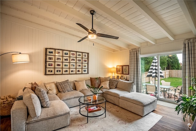 living room featuring wood-type flooring, wood walls, beam ceiling, and ceiling fan