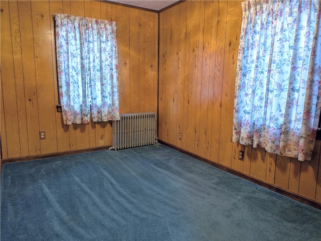 unfurnished room with radiator, wooden walls, and carpet flooring