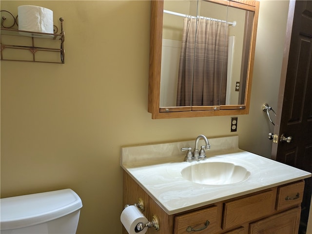 bathroom with walk in shower, vanity, and toilet