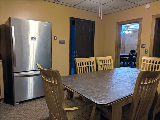 carpeted dining space with a drop ceiling and ceiling fan