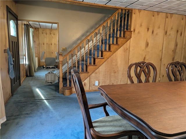 carpeted dining space featuring wooden walls