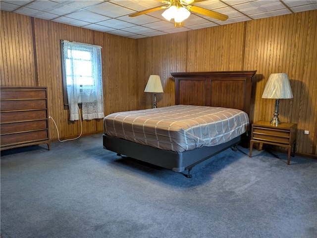 bedroom featuring ceiling fan, wood walls, and carpet flooring