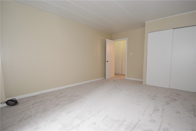 unfurnished bedroom featuring light carpet and a closet