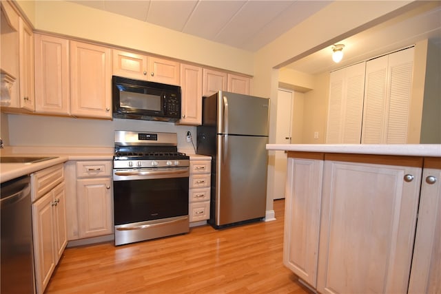 kitchen with appliances with stainless steel finishes, light wood-type flooring, and sink