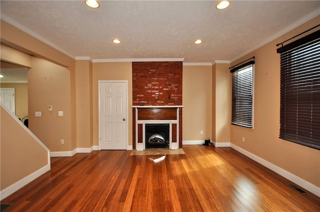 unfurnished living room featuring a textured ceiling, wood-type flooring, a fireplace, and ornamental molding