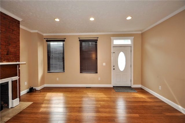 foyer entrance featuring light wood-type flooring, a textured ceiling, and ornamental molding