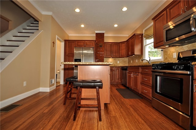 kitchen with light stone counters, appliances with stainless steel finishes, dark hardwood / wood-style floors, and a kitchen island