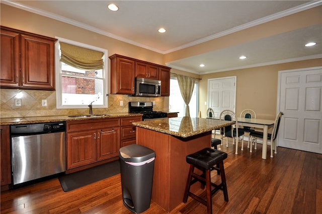 kitchen featuring appliances with stainless steel finishes, crown molding, a center island, dark hardwood / wood-style floors, and sink