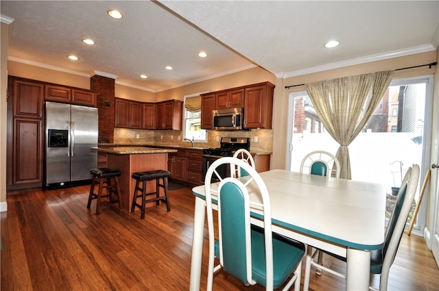 dining room featuring a healthy amount of sunlight, crown molding, dark hardwood / wood-style floors, and sink