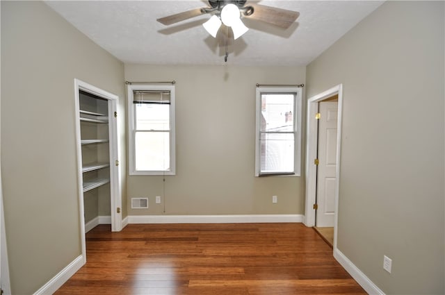 unfurnished bedroom with multiple windows, a textured ceiling, ceiling fan, and dark wood-type flooring