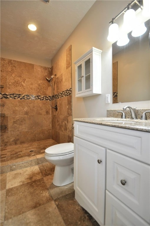 bathroom featuring tiled shower, vanity, and toilet