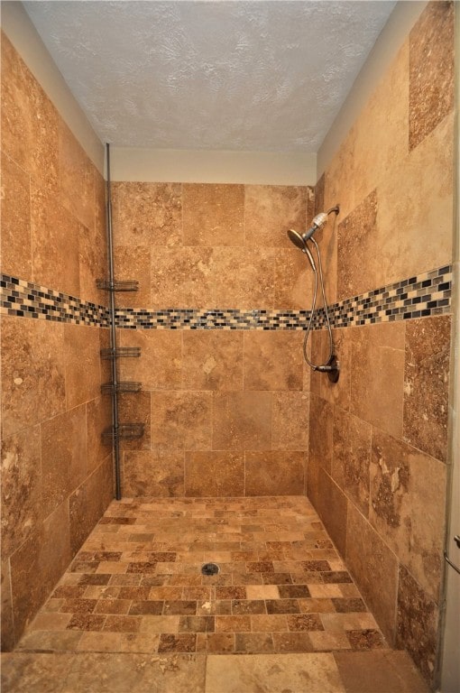 bathroom featuring a textured ceiling and tiled shower