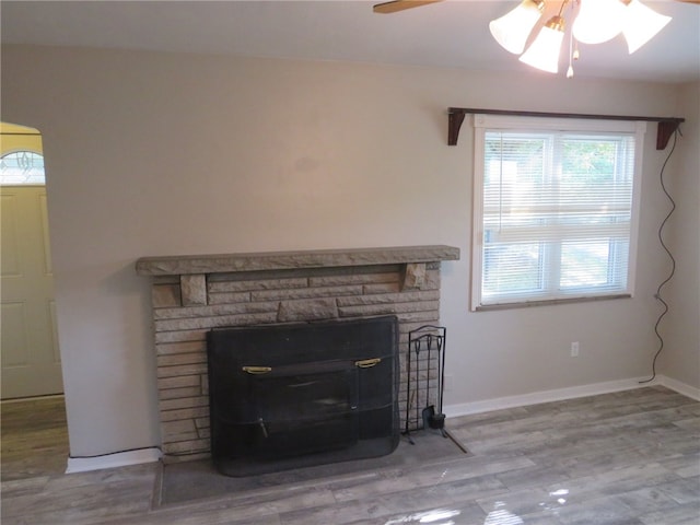 room details featuring hardwood / wood-style flooring, ceiling fan, and a stone fireplace