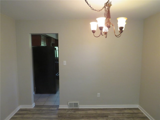 empty room featuring hardwood / wood-style floors and a chandelier