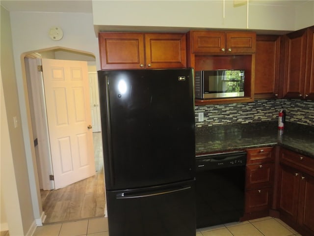 kitchen featuring black appliances, light hardwood / wood-style flooring, tasteful backsplash, and dark stone countertops