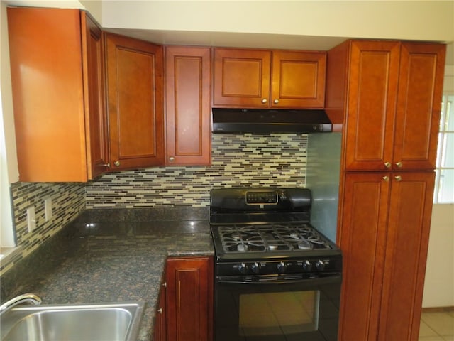 kitchen with sink, decorative backsplash, dark stone counters, and black gas stove