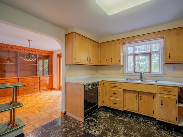 kitchen featuring pendant lighting, black dishwasher, dark parquet flooring, and sink