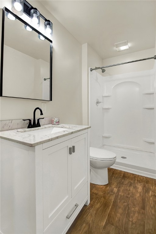 bathroom with wood-type flooring, a shower, vanity, and toilet