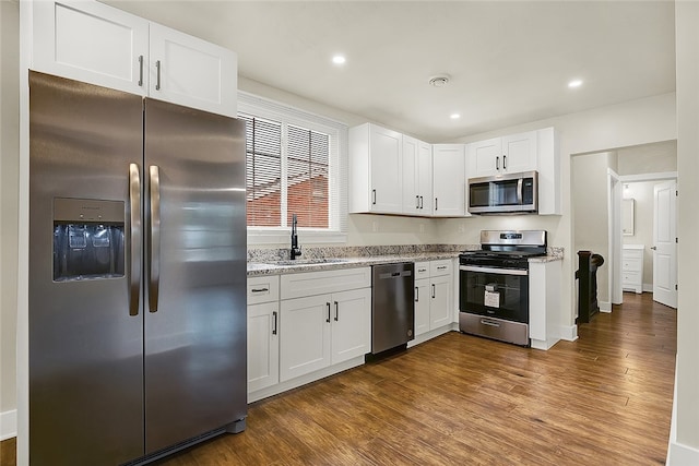 kitchen with white cabinets, appliances with stainless steel finishes, dark hardwood / wood-style floors, and sink