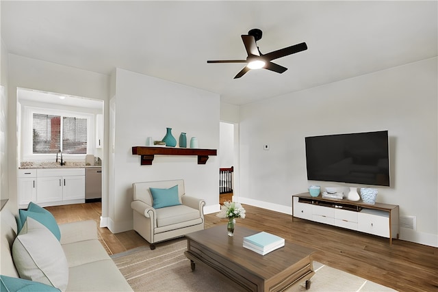 living room with light hardwood / wood-style flooring, ceiling fan, and sink