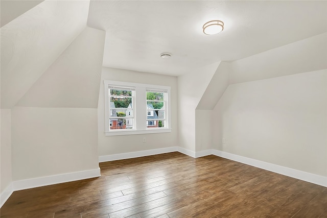 additional living space featuring lofted ceiling and dark wood-type flooring